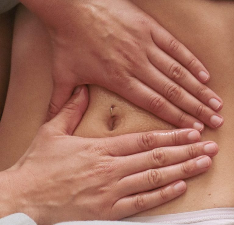 Deux mains massent le ventre d'une personne, mettant l'accent sur le nombril.