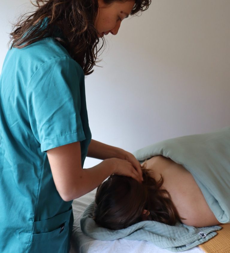 Une thérapeute masse les cervicales d'une cliente allongée sur une table.