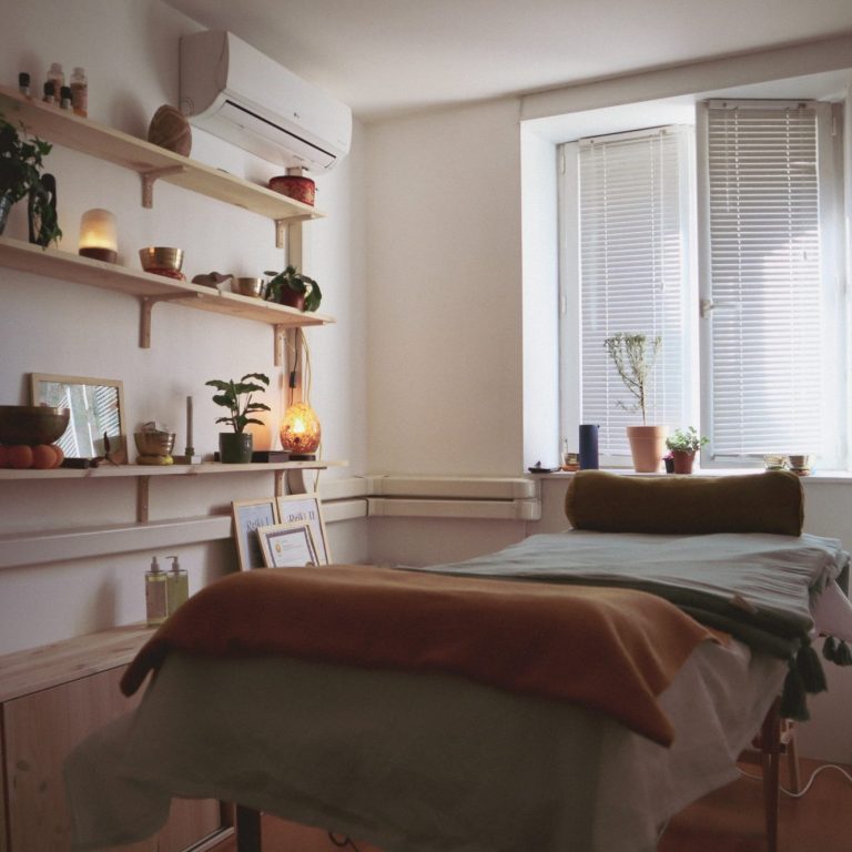 Salle de soin apaisante avec lit, plantes et étagères décoratives.