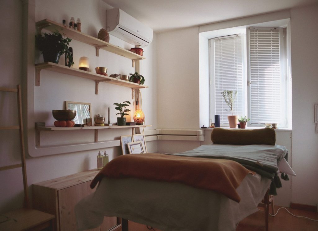 Salle de soins avec un lit, des plantes et des étagères décorative. Ambiance chaleureuse et détendant. 